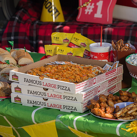 Pizza party table with wings, pizza, subs, candy, and more.