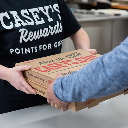 Casey's Team Member handing pizzas to guest