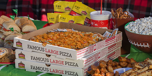 Pizza party table with wings, pizza, subs, candy, and more.